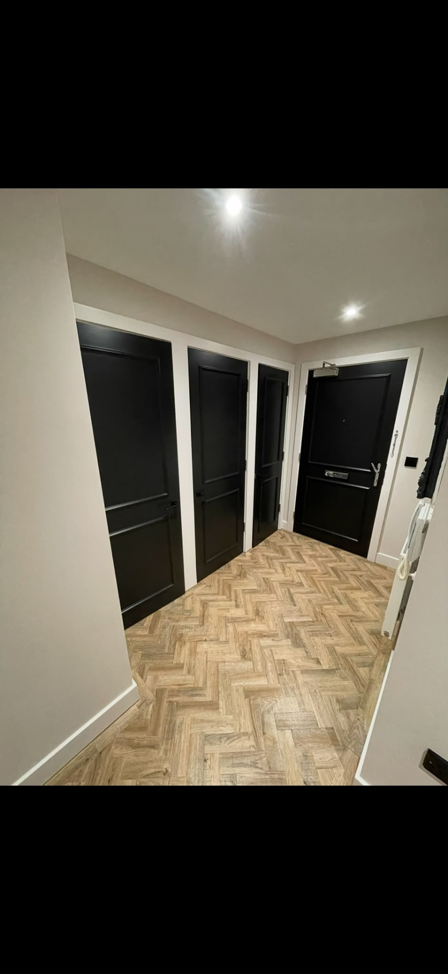 Entrance hallway with four hand-painted black panelled doors and crisp white frames, Brighton